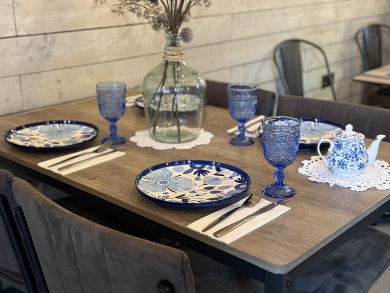 Tavolo con maioliche e bicchieri blu – Pane Cunzato