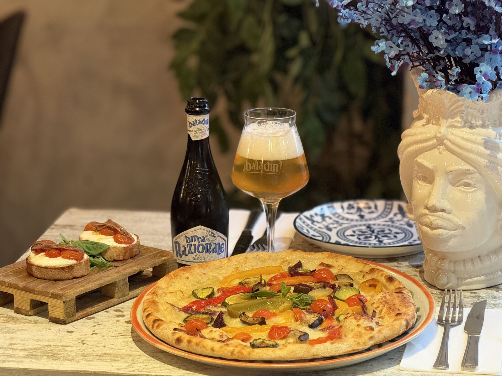 Pizza and Baladin beer beside a Sicilian testa di moro